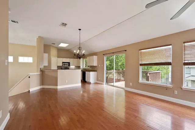 a view of a kitchen and an empty room with wooden floor and a kitchen