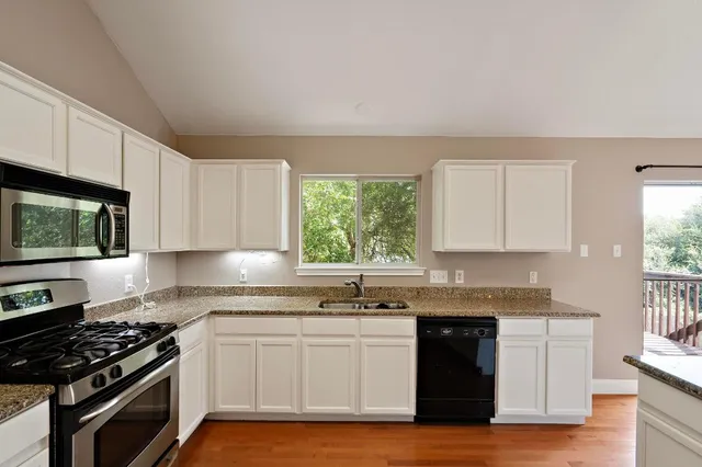 a kitchen with granite countertop stainless steel appliances a stove sink and cabinets