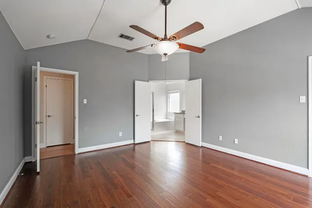a view of an empty room with a window and wooden floor