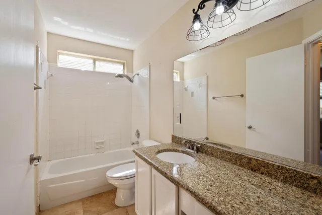 a bathroom with a granite countertop sink a toilet and shower