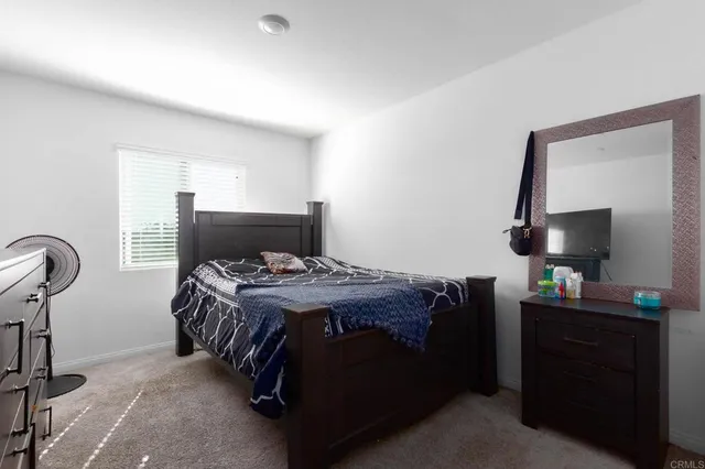 a bedroom with a bed and a flat tv screen on the dresser