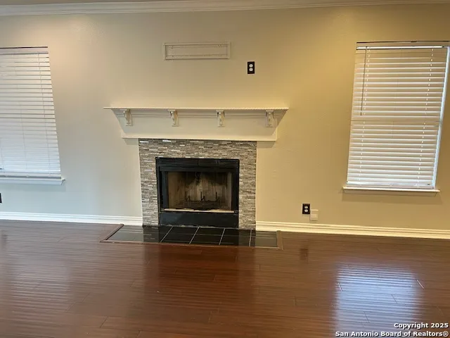 a view of an empty room with wooden floor and a fireplace