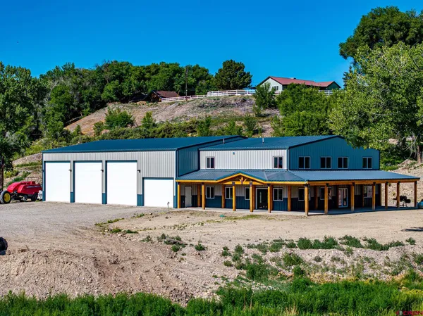 a view of a kitchen with stainless steel appliances granite countertop a refrigerator a stove a microwave oven a dining table and chairs with wooden floor