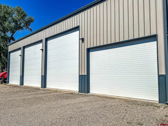 a view of a kitchen with stainless steel appliances granite countertop a refrigerator a stove a microwave oven a dining table and chairs with wooden floor