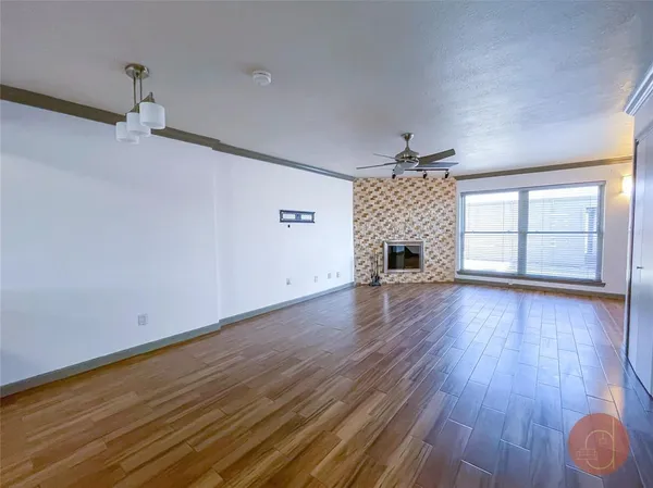 an empty room with wooden floor fireplace and windows