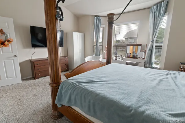 a bedroom with a bed flat screen tv and a large window