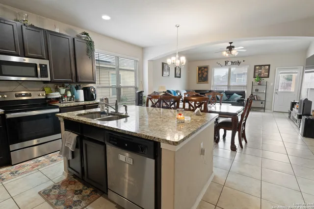 a kitchen with stainless steel appliances granite countertop a sink a stove a dining table and chairs