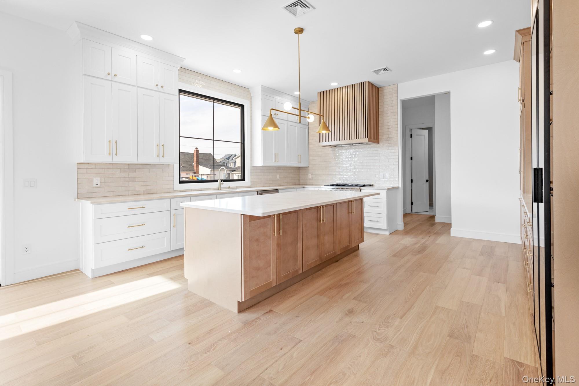 24 Midway Street Babylon, NY 11702 - Photo 11 of 40 Kitchen featuring a center island, hanging light fixtures, light wood finished floors, backsplash, and recessed lighting