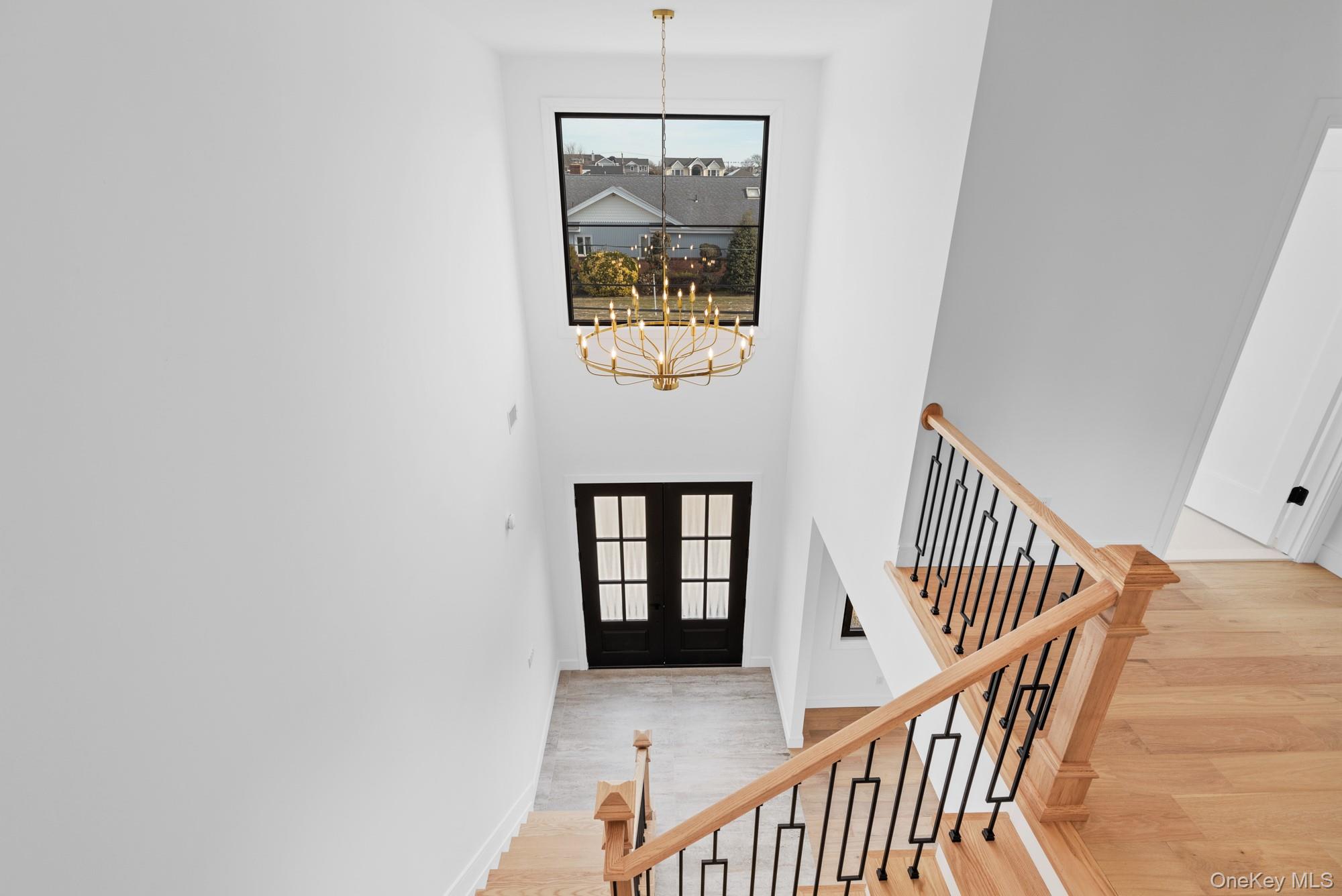 24 Midway Street Babylon, NY 11702 - Photo 17 of 40 Entrance foyer with a chandelier, french doors, light wood-style floors, and a towering ceiling
