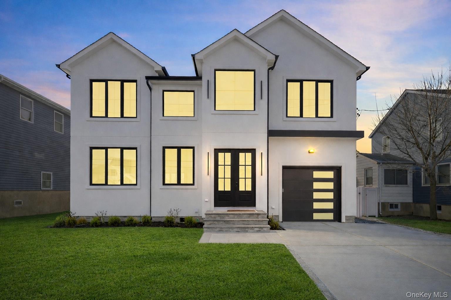 24 Midway Street Babylon, NY 11702 - Photo 2 of 40 Contemporary home with a lawn, driveway, stucco siding, and an attached garage