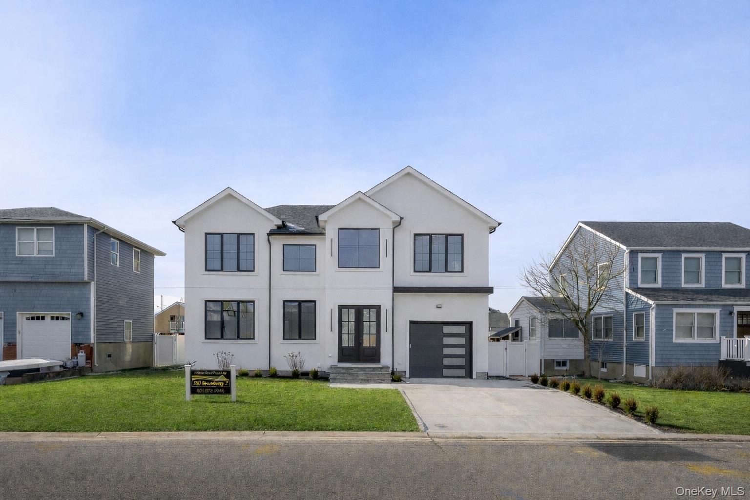24 Midway Street Babylon, NY 11702 - Photo 3 of 40 View of front of home featuring a front lawn, concrete driveway, stucco siding, and an attached garage