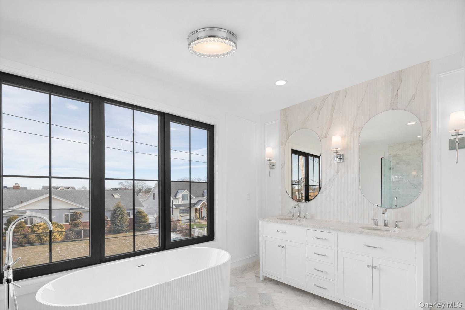 24 Midway Street Babylon, NY 11702 - Photo 34 of 40 Bathroom featuring double vanity, a freestanding bath, recessed lighting, and light marble finish floors