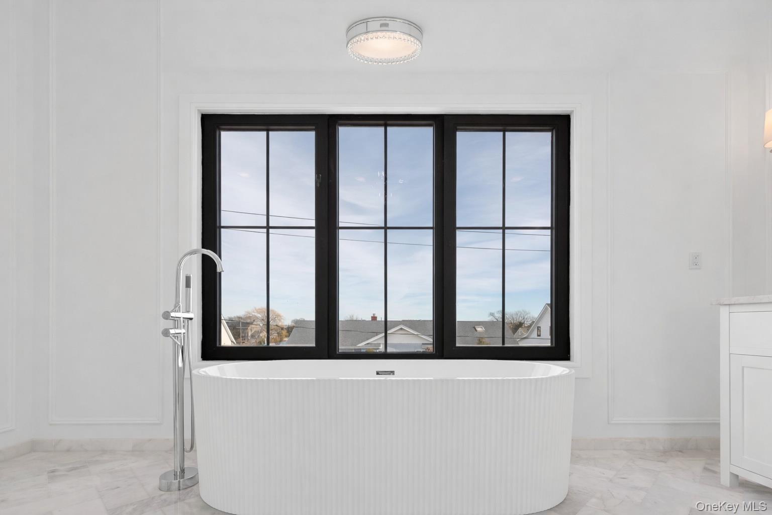 24 Midway Street Babylon, NY 11702 - Photo 35 of 40 Full bathroom featuring light marble finish floors, a freestanding tub, and plenty of natural light