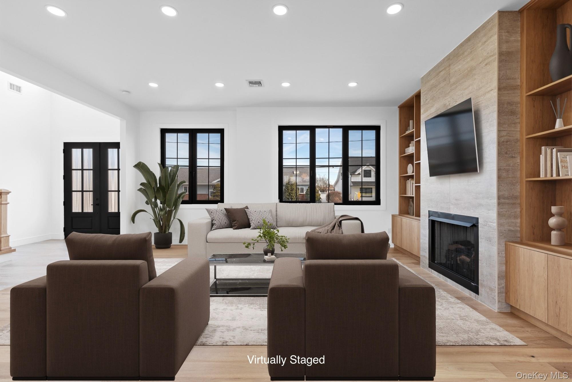 24 Midway Street Babylon, NY 11702 - Photo 8 of 40 Living room with a large fireplace, light wood-style floors, recessed lighting, healthy amount of natural light, and built in features