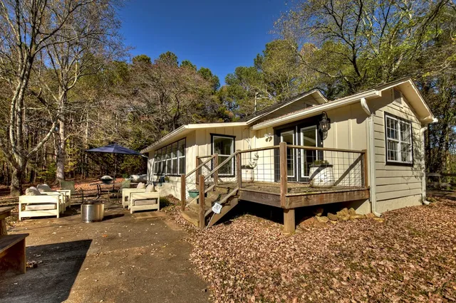 a white house that has a small yard and large trees