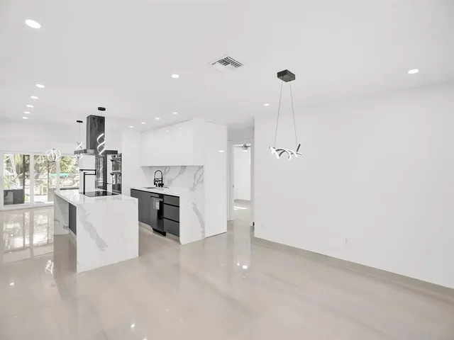 a view of kitchen with kitchen island a refrigerator a stove and a dining table with wooden floor