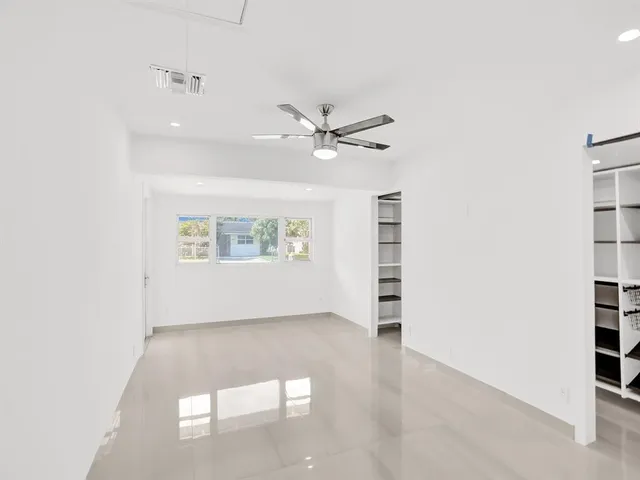 an empty room with windows and ceiling fan
