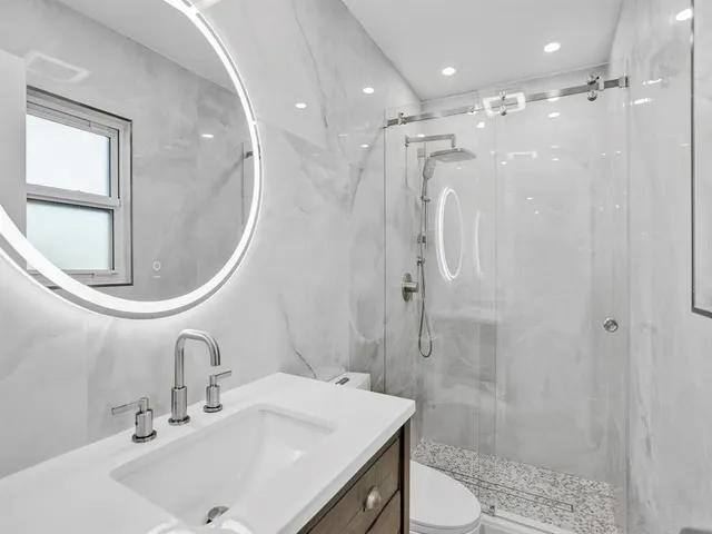 a bathroom with a sink a toilet and shower