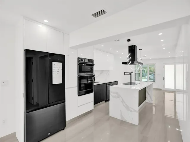 a kitchen with stainless steel appliances kitchen island granite countertop a sink and a refrigerator