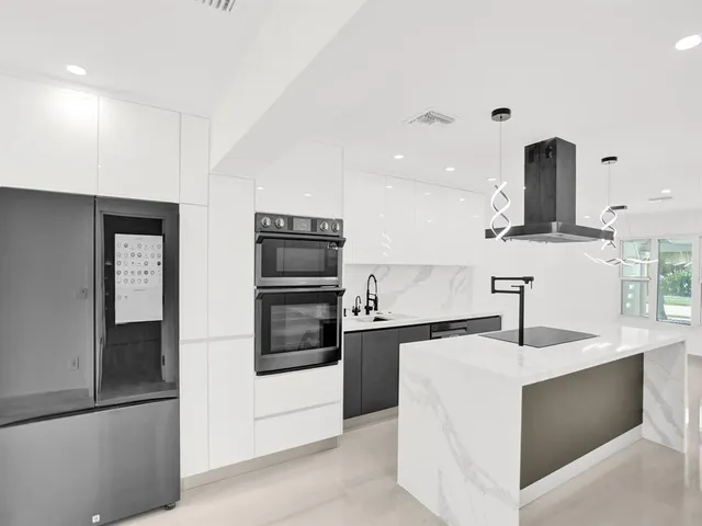 a view of kitchen with stainless steel appliances refrigerator oven and white cabinets with wooden floor