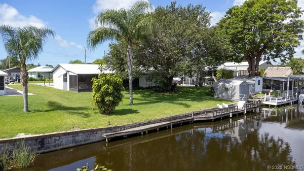 a view of swimming pool with lawn chairs and a large tree