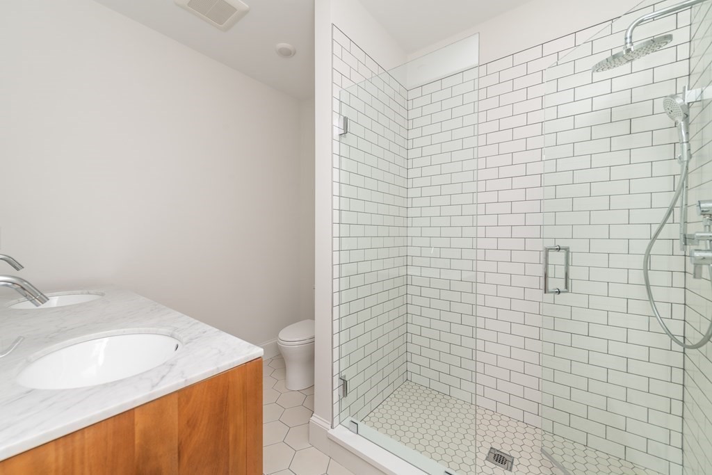 120 Brookside Avenue, Unit 203 Boston, MA 02130 - Photo 16 of 18 a bathroom with a granite countertop sink a toilet and shower