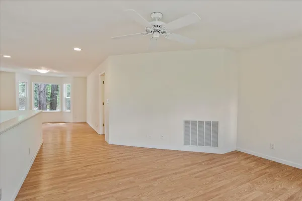 a view of empty room with wooden floor and fan