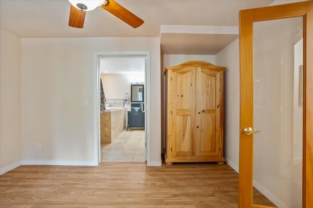 a view of an empty room with wooden floor and a ceiling fan