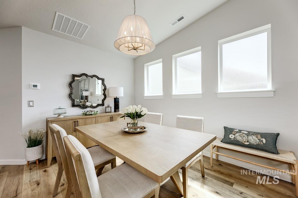 348 West Radiant Rdg Drive Meridian, ID 83642 - Photo 10 of 36 Vaulted ceiling, wood-finish flooring, three vertical windows, built-in recessed lighting, and a drum pendant light fixture