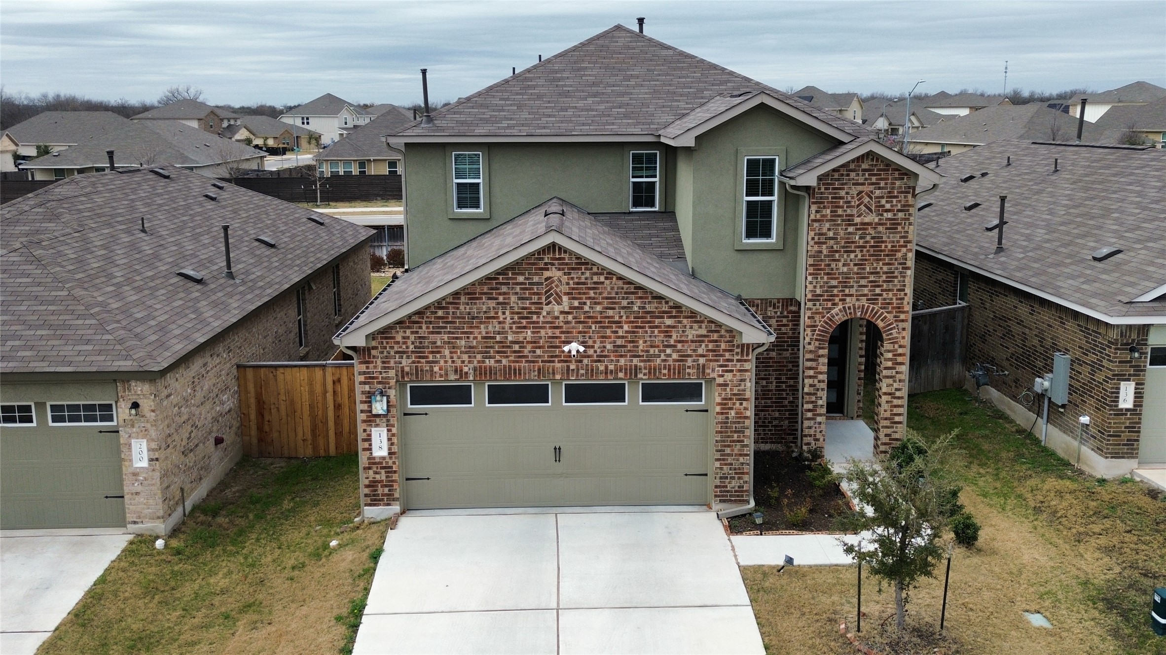 Traditional home featuring stucco siding, driveway, brick siding, and a residential view