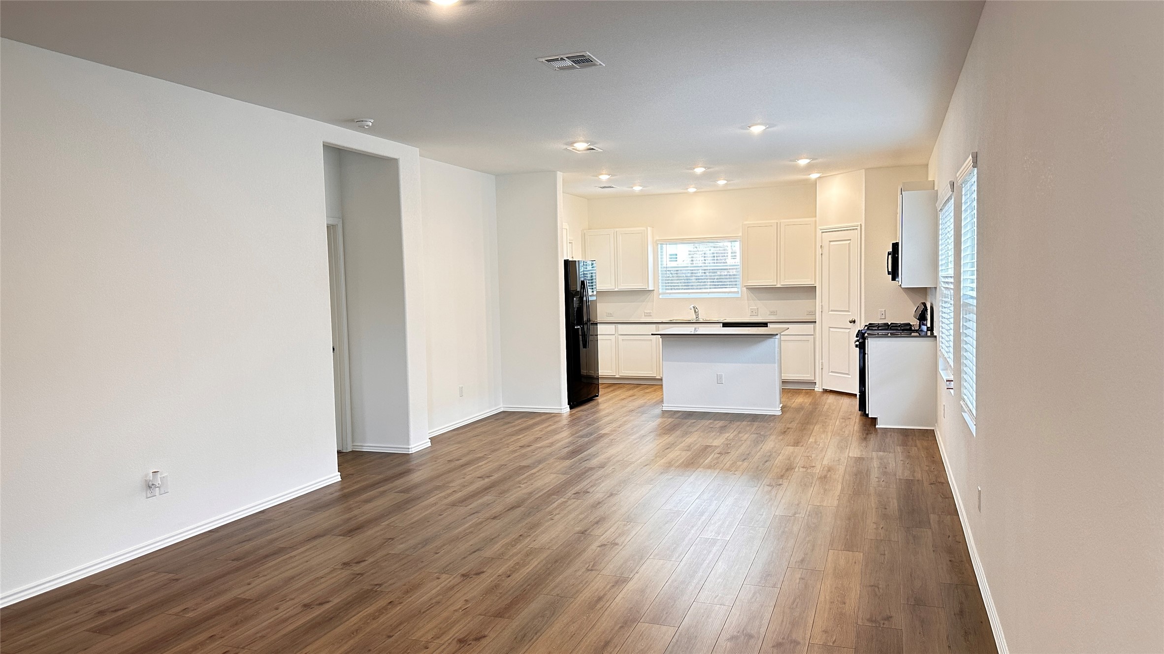 138 Milliner Loop Hutto, TX 78634 - Photo 7 of 36 Kitchen with white cabinetry, a kitchen island, dark wood-type flooring, freestanding refrigerator, and light countertops