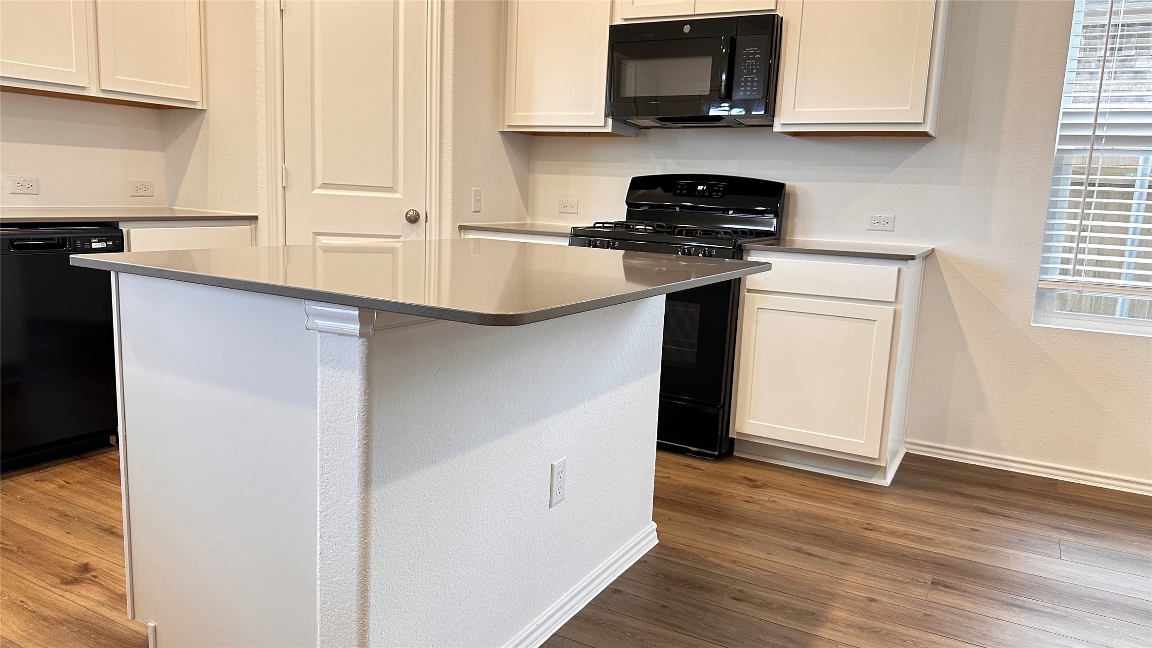 138 Milliner Loop Hutto, TX 78634 - Photo 9 of 36 Kitchen featuring black appliances, white cabinets, a kitchen island, and dark wood finished floors