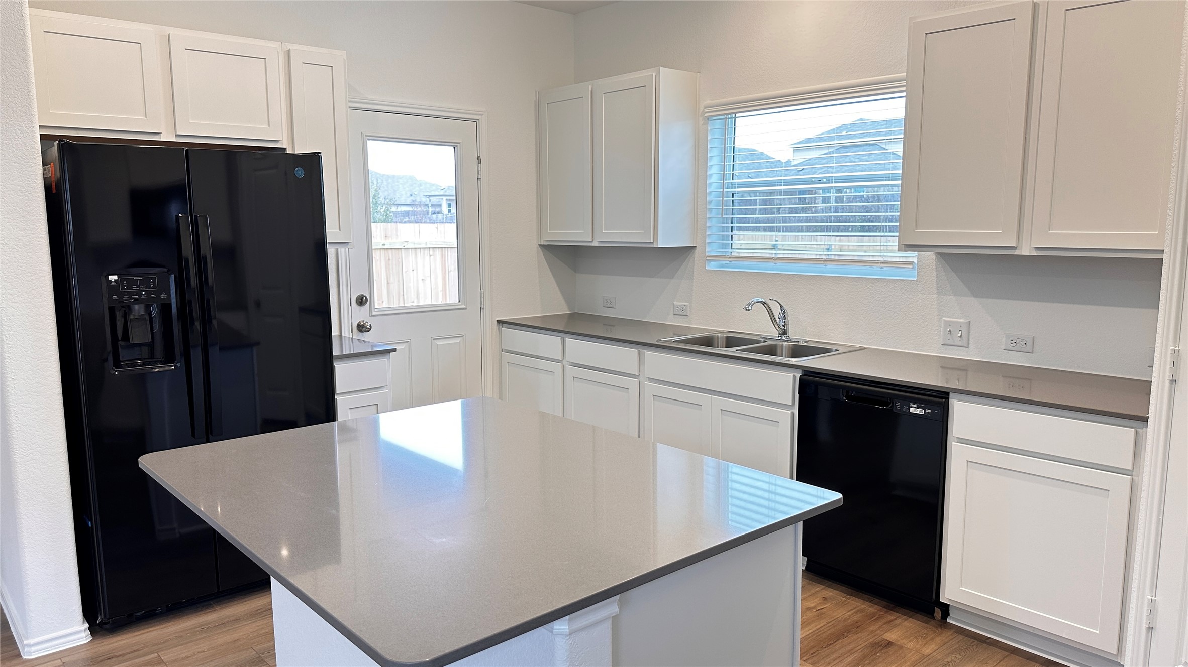 138 Milliner Loop Hutto, TX 78634 - Photo 10 of 36 Kitchen featuring black appliances, light wood-style flooring, white cabinets, and a center island