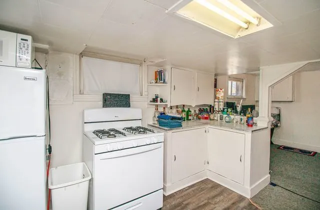 a kitchen with refrigerator a stove a sink dishwasher and white cabinets with wooden floor
