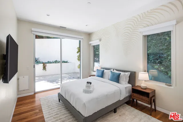 a bedroom with a bed a large window and a flat tv screen