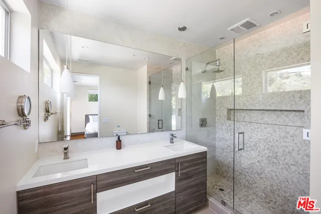 a bathroom with a double vanity sink mirror and shower