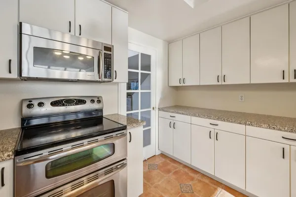 a kitchen with granite countertop white cabinets stainless steel appliances and a sink