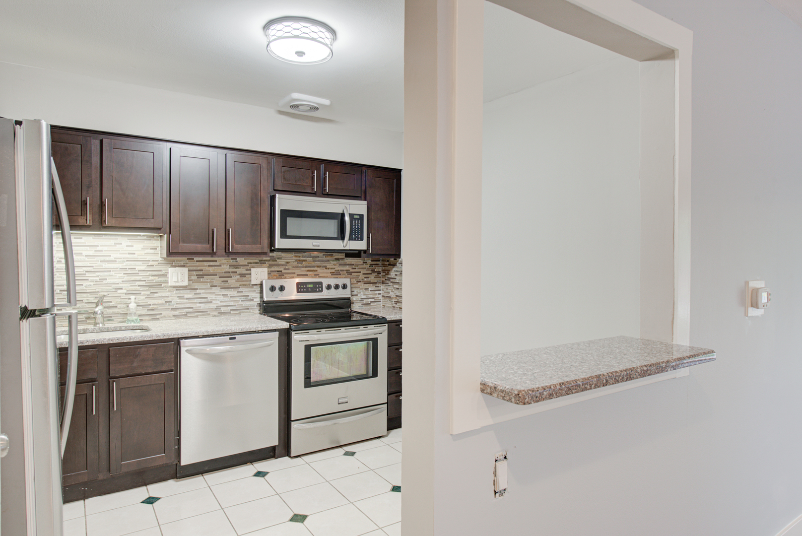 2323 South Goebbert Road, Unit 109 Arlington Heights, IL 60005 - Photo 7 of 22 a kitchen with stainless steel appliances granite countertop a stove a sink and a microwave