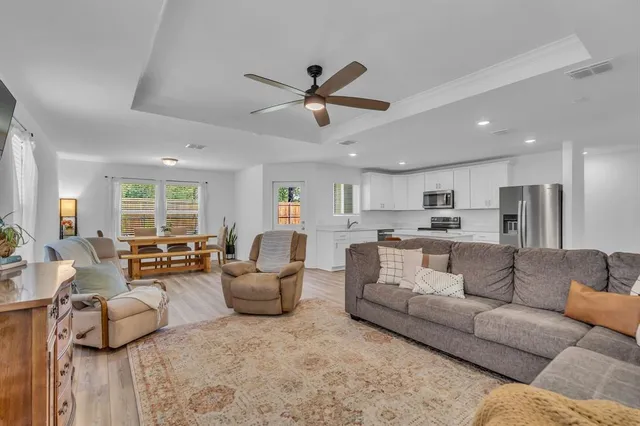 a living room with furniture kitchen view and a large window