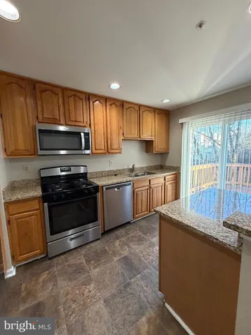 a kitchen with granite countertop a stove a sink and a microwave