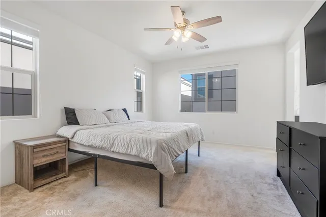 a spacious bedroom with a bed and a flat screen tv