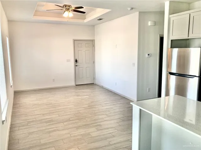 a view of a kitchen with a refrigerator a ceiling fan and wooden floor