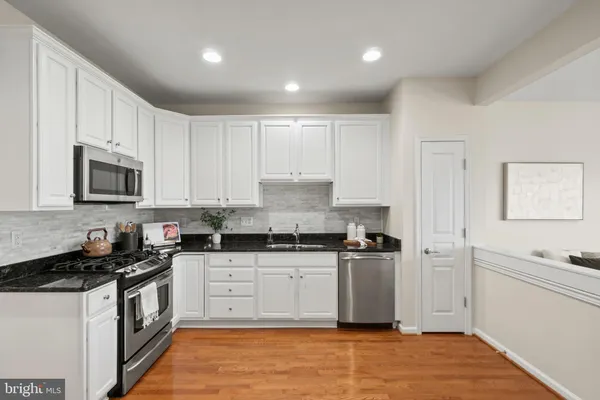 a kitchen with granite countertop a sink a stove and refrigerator