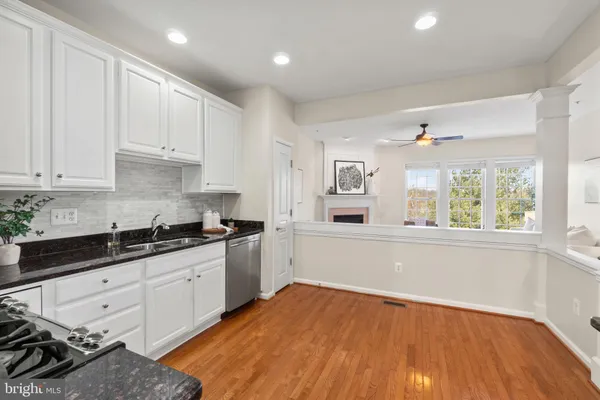 a kitchen with stainless steel appliances granite countertop a stove a sink and white cabinets