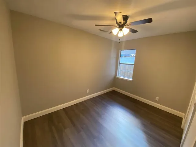 an empty room with wooden floor and ceiling fan