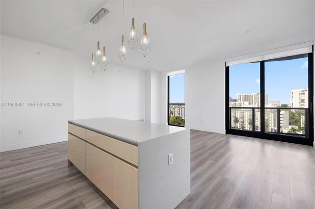 a large kitchen with kitchen island a stove a sink a refrigerator and white cabinets with wooden floor