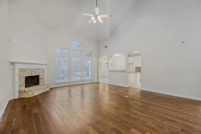 a view of a livingroom with a fireplace a chandelier fan and wooden floor