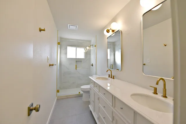a bathroom with a double vanity sink mirror and shower