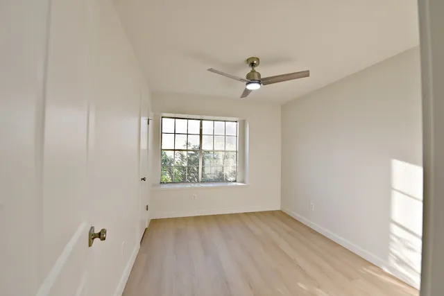 an empty room with a window and a ceiling fan