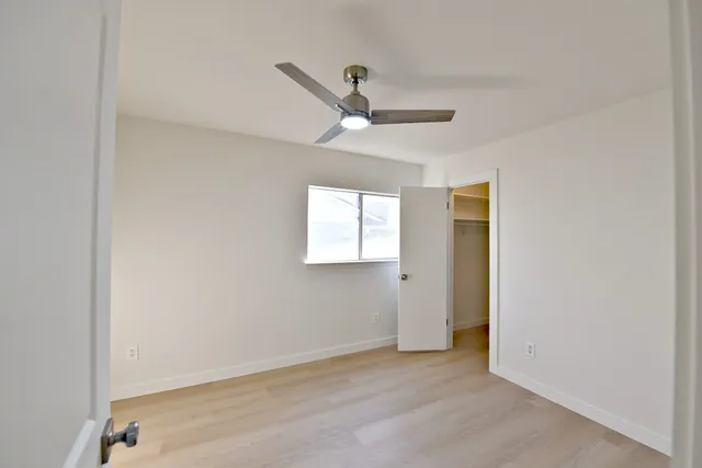 an empty room with a window and a ceiling fan